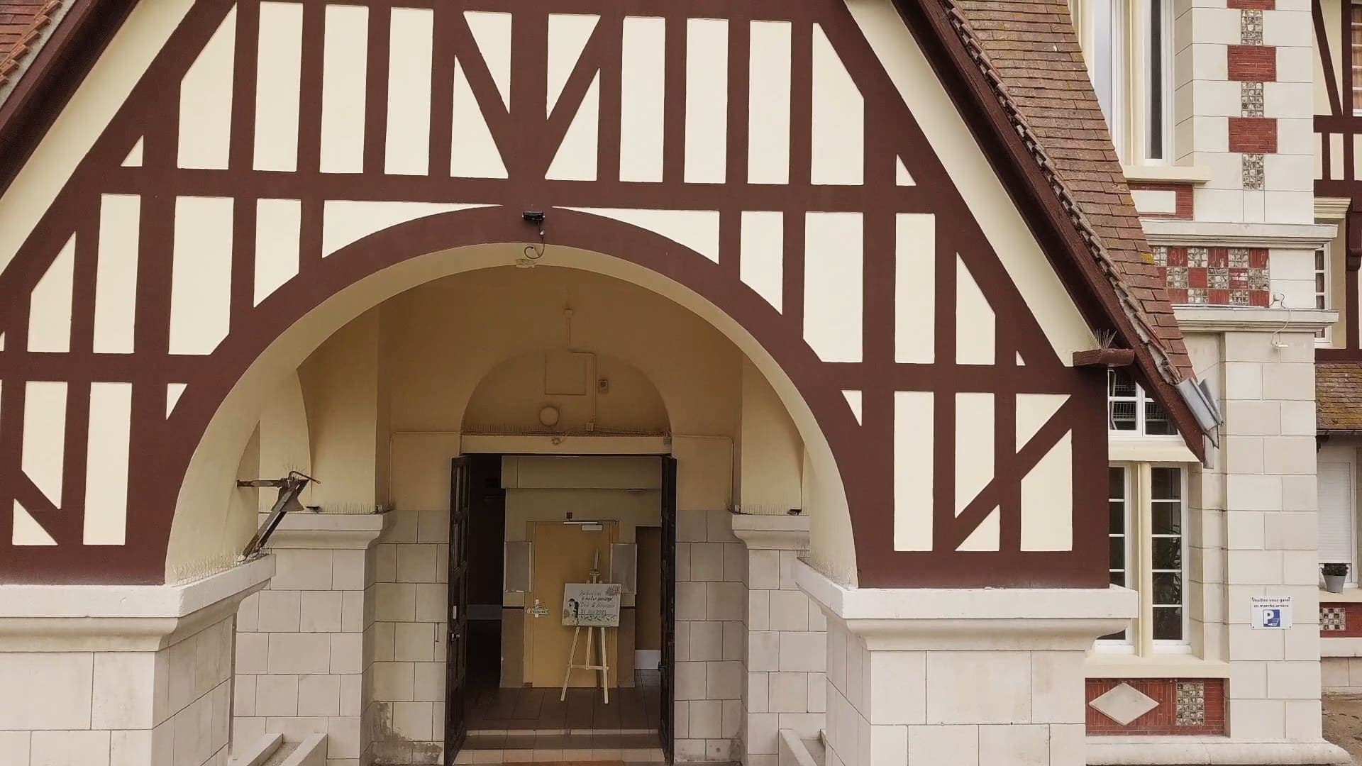 Le porche de l’église, une arche de pierre sous un pignon à colombages.